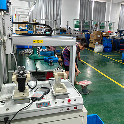 Trabajador de fábrica que utiliza una pulidora de doble acción en un taller bien equipado, rodeado de diversas herramientas y maquinaria para detallar automóviles.